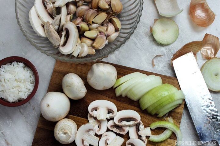 mushrooms, onions being sliced on a cutting board.