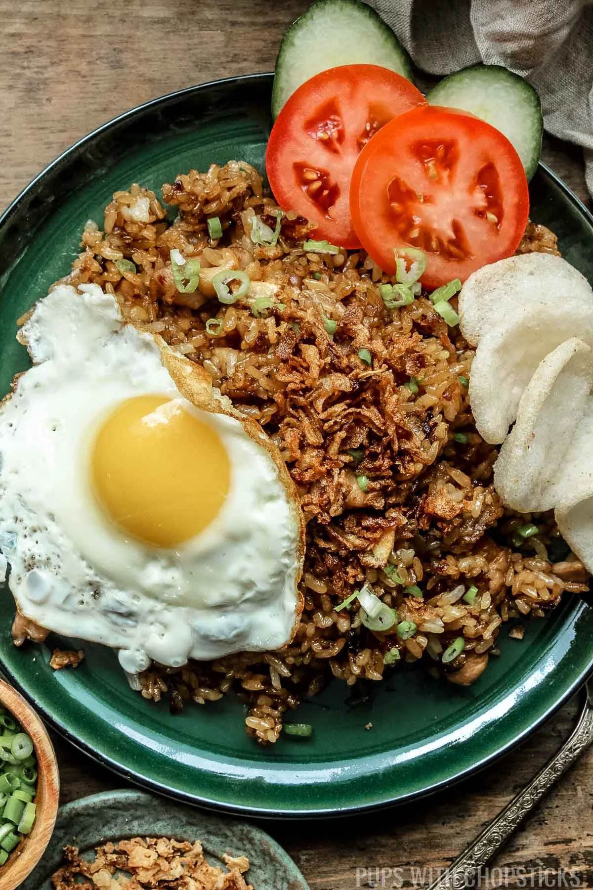 Nasi goreng (Indonesian fried rice) with prawn crackers, fried egg on a green plate.