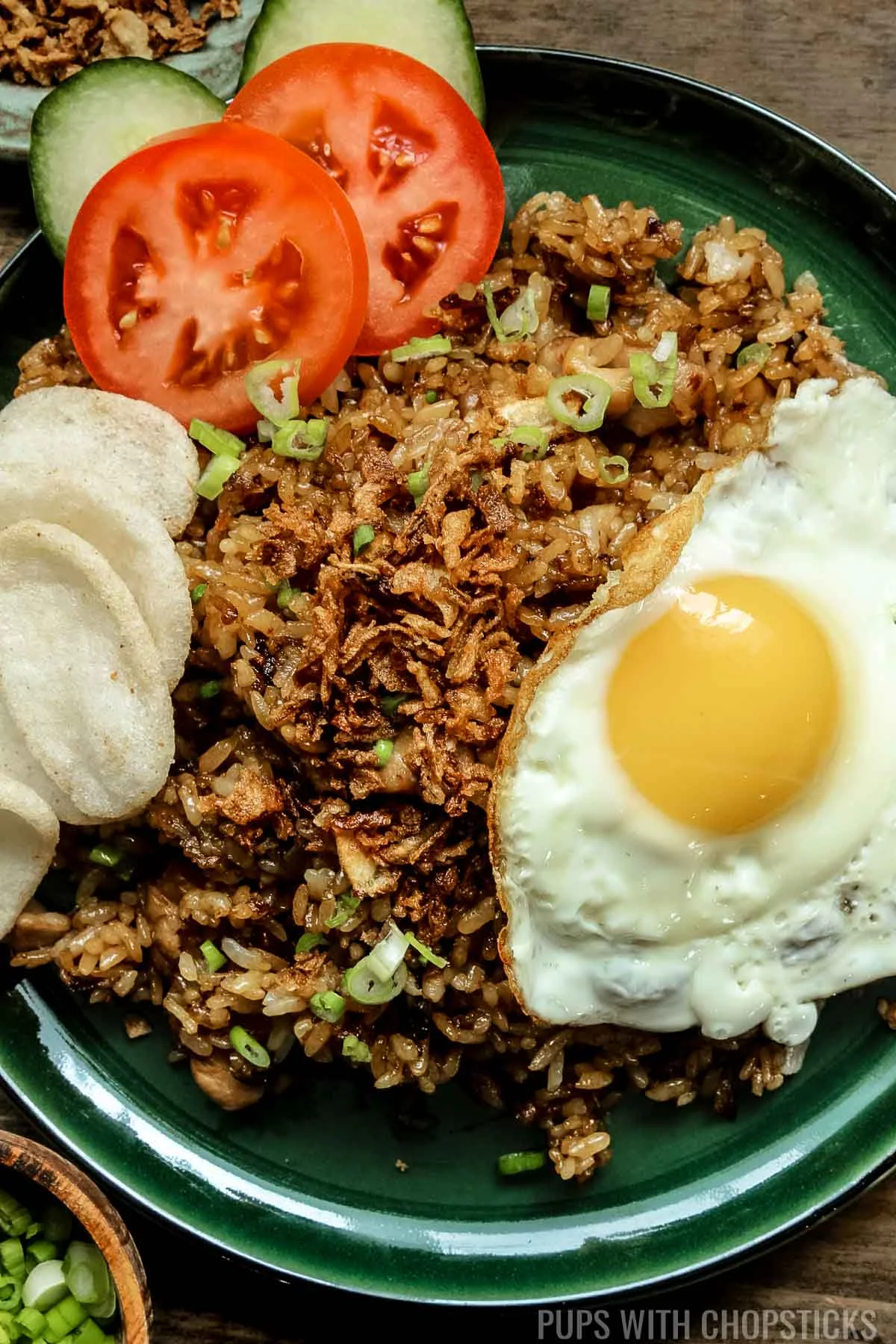 Closeup of nasi goreng (Indonesian fried rice) with a fried egg on a green plate.