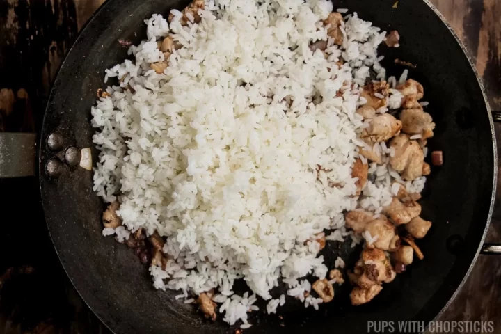 Adding rice to the frying pan for nasi goreng.