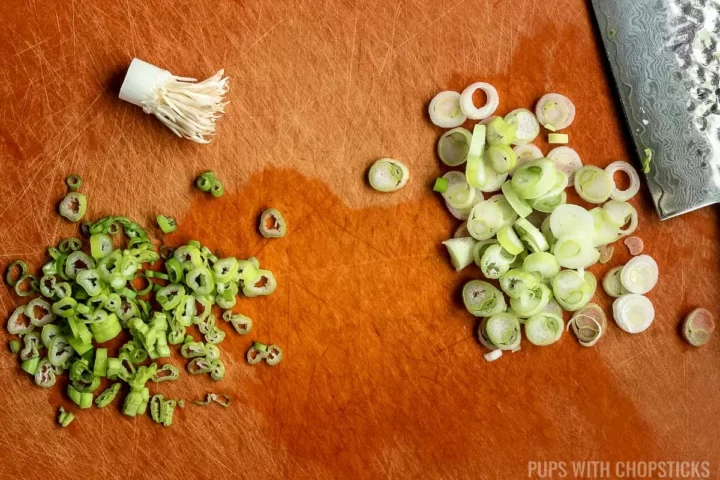 Chopping green onions for nasi goreng, separating the greens and the whites on a cutting board.