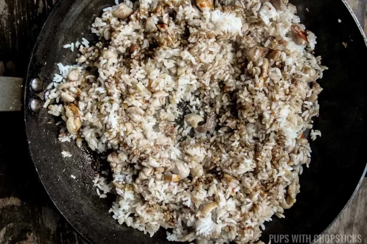 Add kecap manis to the nasi goreng in the frying pan.