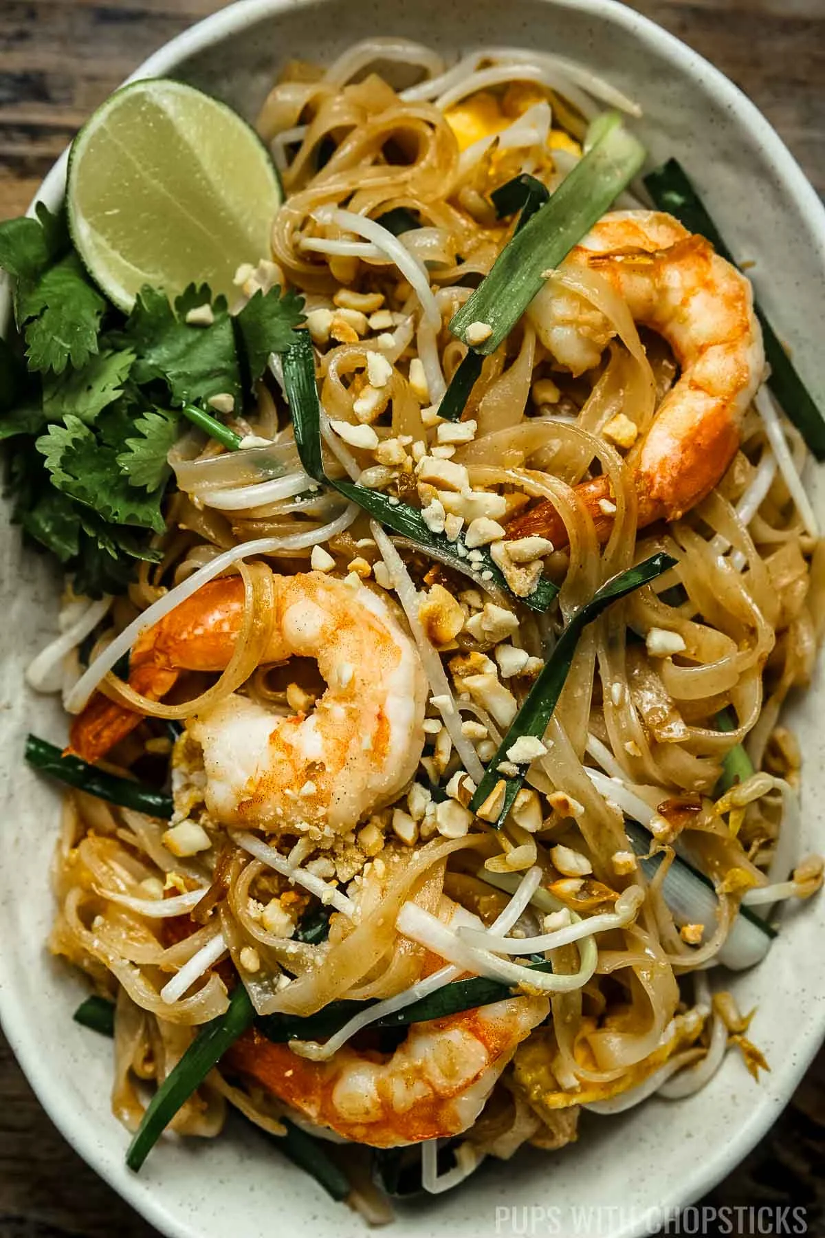 Closeup of pad thai with shrimp and lime wedges