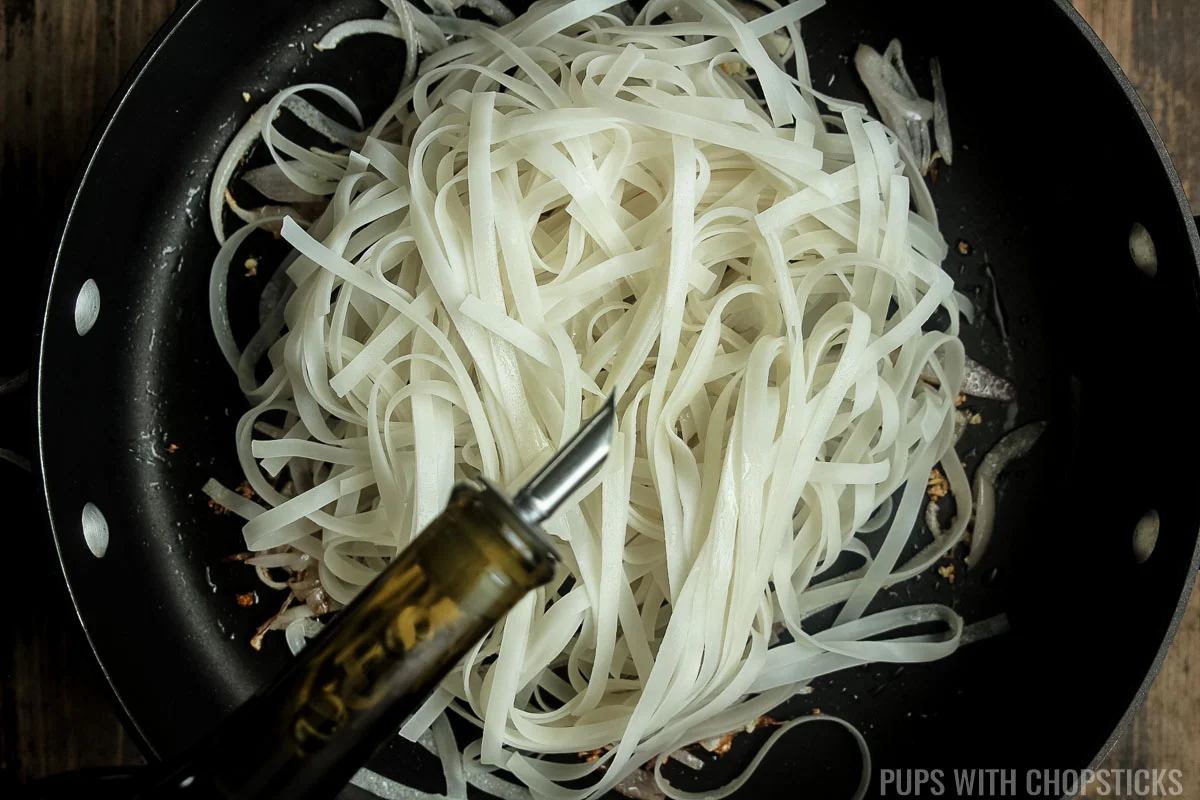 Rice noodles added to the frying pan with a drizzle of oil.