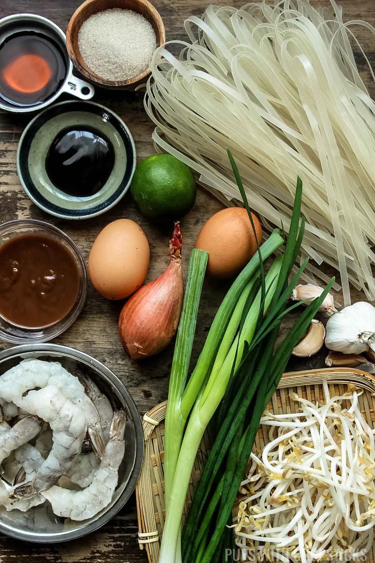 Ingredients mise en place for pad thai (rice noodles, tamarind paste, fish sauce, sugar, eggs, limes, shrimp, bean sprouts)