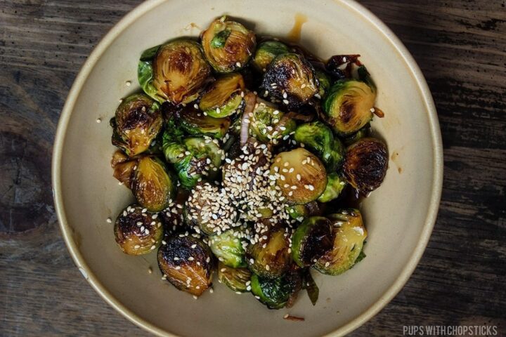 Honey Glazed Pan Fried Brussels Sprouts topped with sesame seeds and served in a large bowl