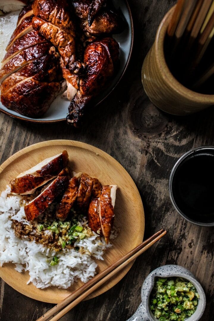Peking chicken being served on a plate with rice and ginger scallion sauce on top