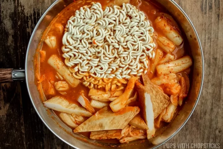 Adding instant ramen into the pot for the rabokki