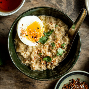 Closeup of savory oatmeal in a green bowl with soft boiled egg