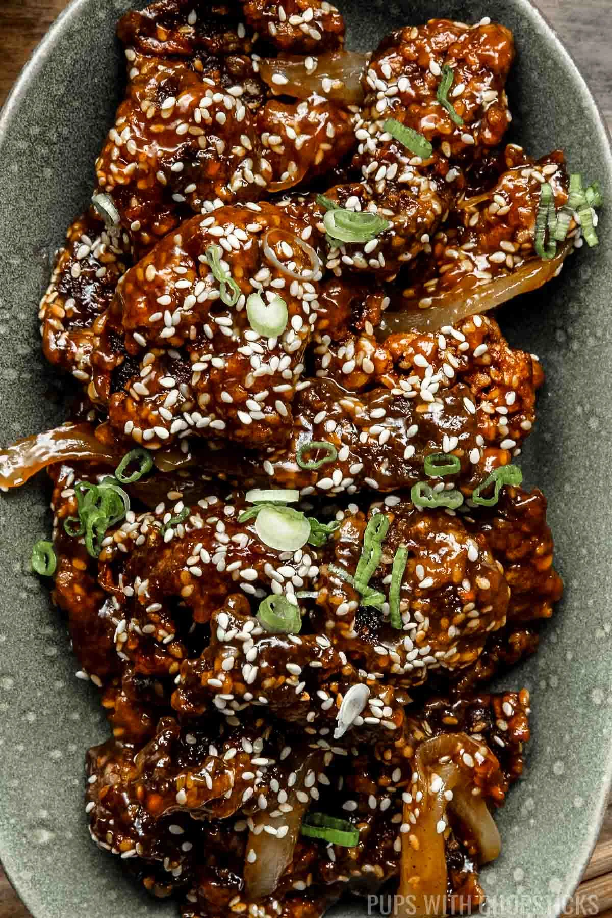 close up of sesame beef in a green bowl.