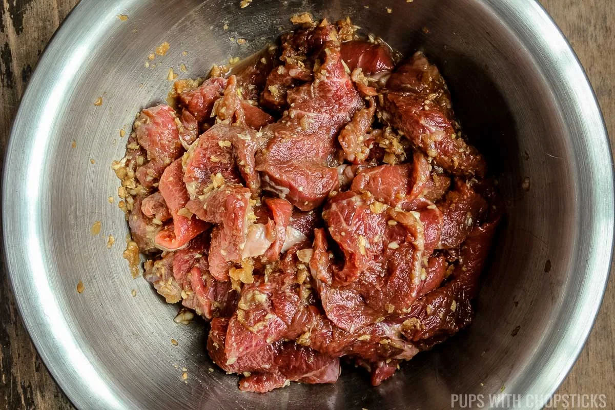 marinating sliced beef in a metal bowl for sesame beef.