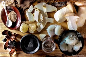 Ingredients for Black Garlic Shirataki Noodles with King Oyster Mushrooms laid out on a cutting board