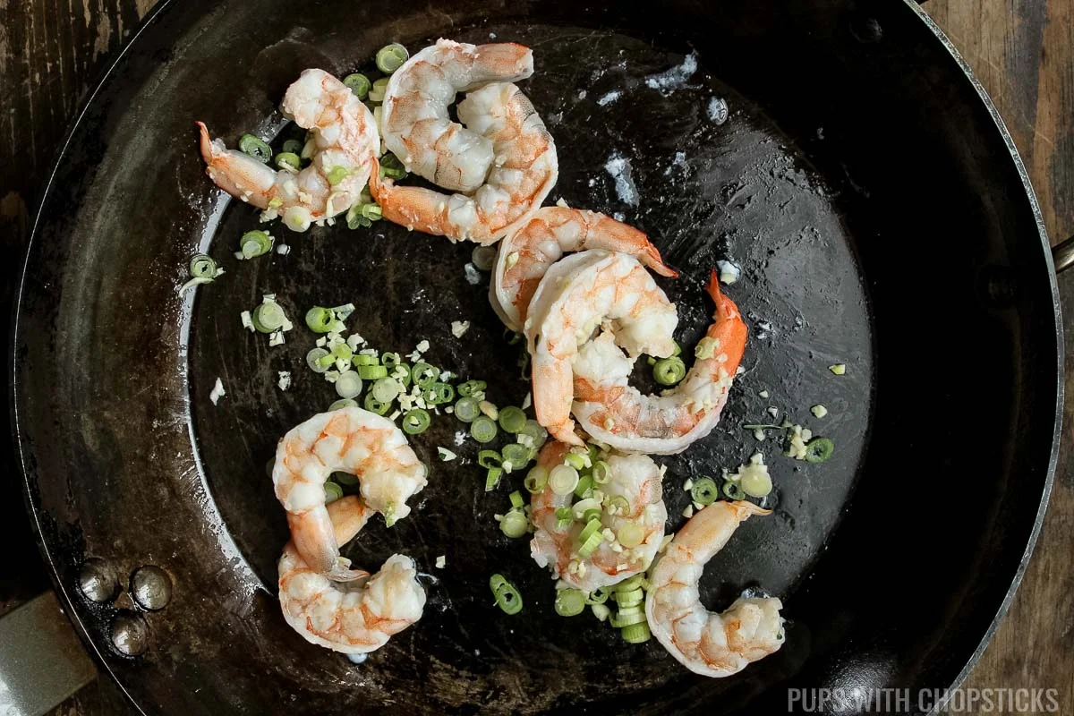 Add garlic and the whites of green onion into the pan with shrimp.