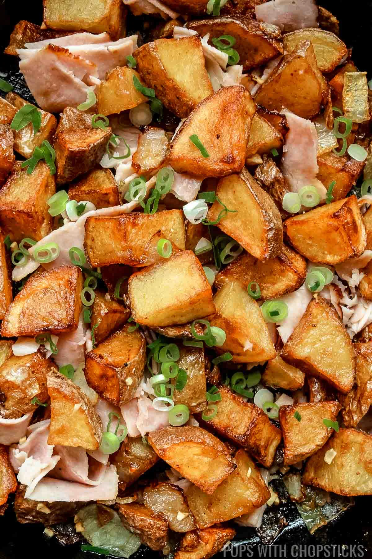 Closeup of skillet potatoes with onions in a cast iron pan