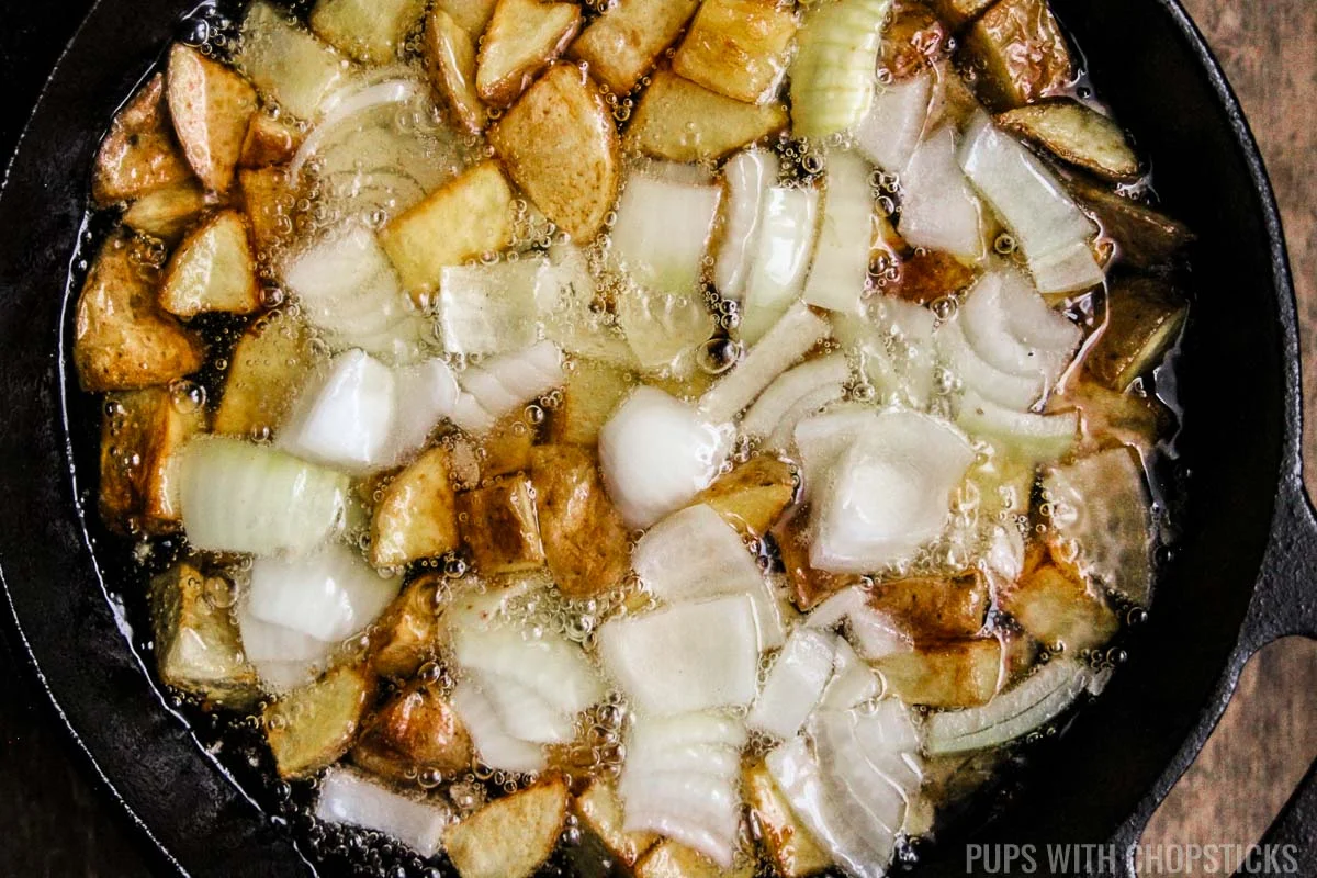 Added onions to the skillet potatoes that are being pan fried