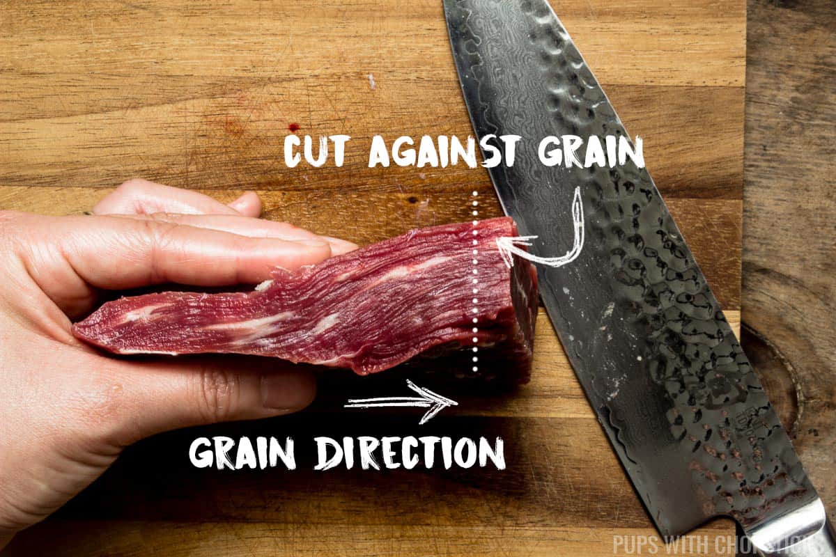 A slab of flank beef being shown how to slice against the grain