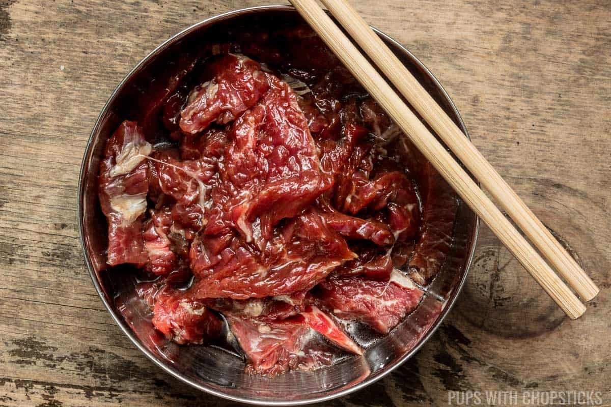 A small bowl of sliced beef being marinated.