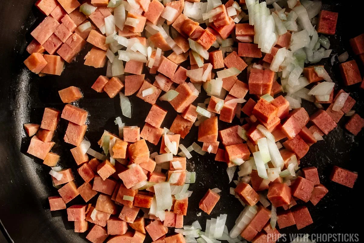 Toasting diced onions with spam in a frying pan