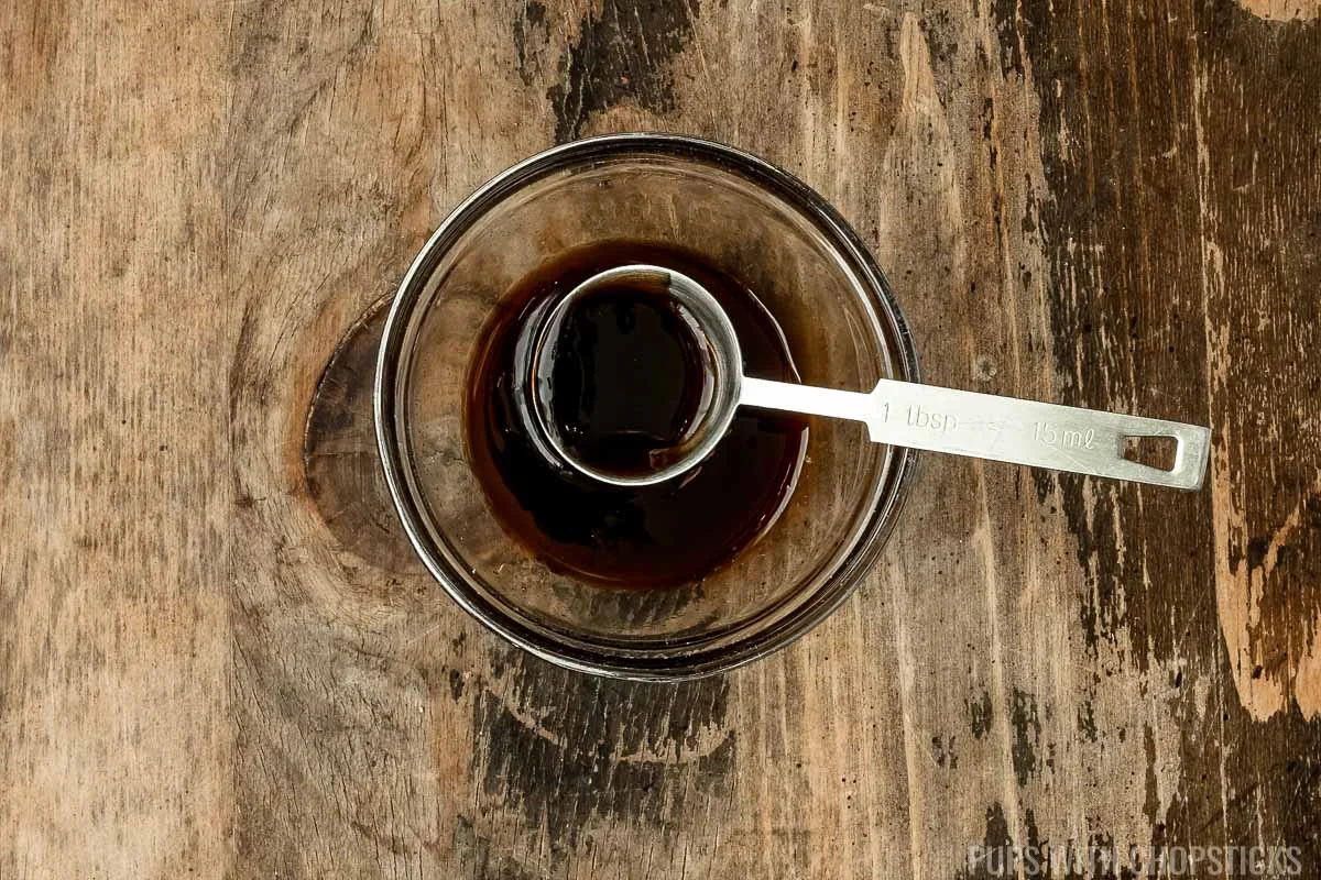 Oyster sauce and soy sauce mix together in a small glass bowl.