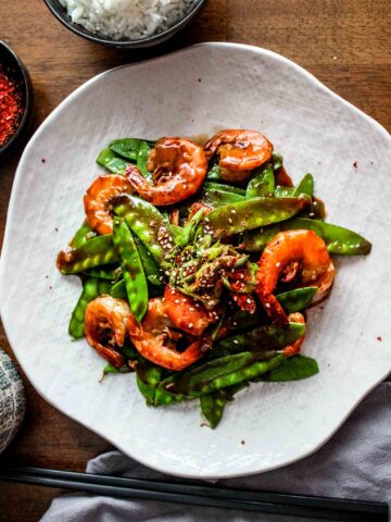 Spicy garlic shrimp with snow peas on a large white plate