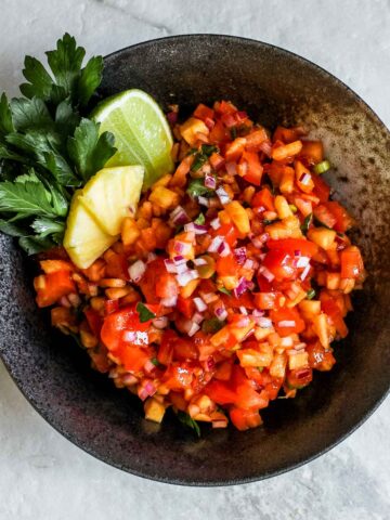 Sweet and spicy pineapple salsa in a black bowl.