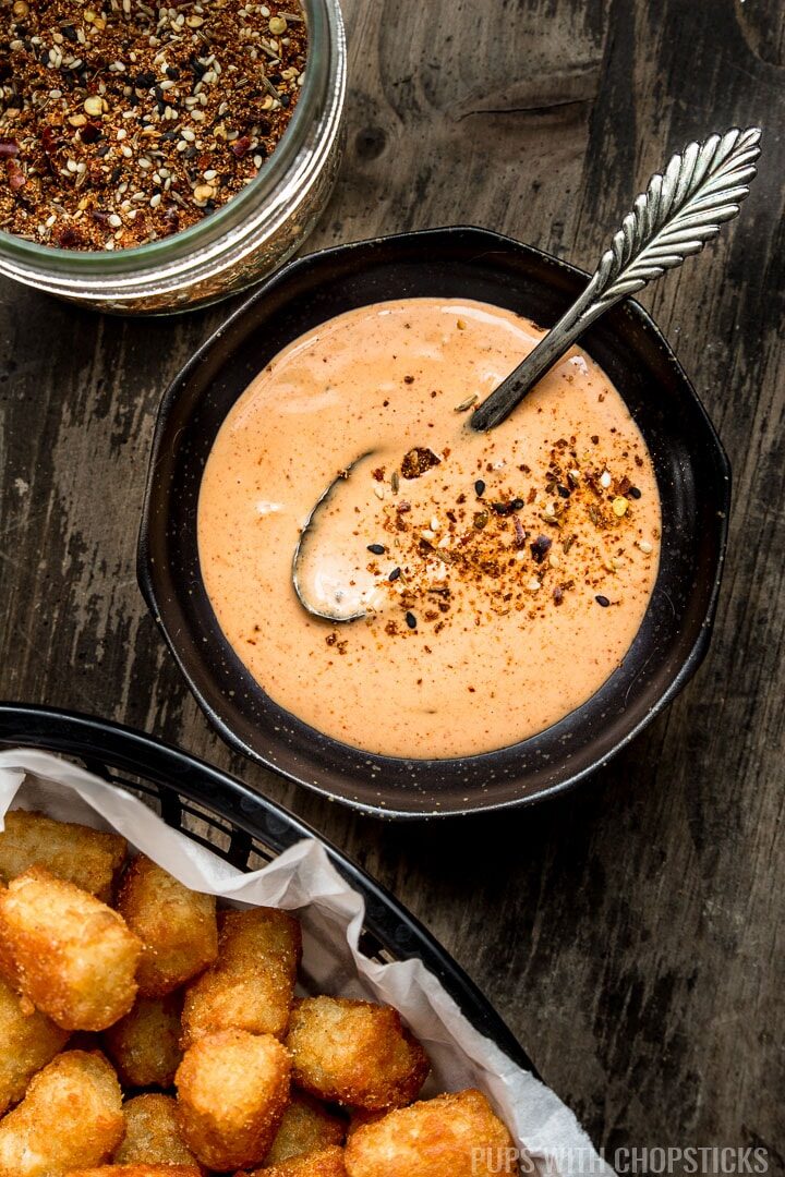 A small bowl of spicy mayo served with a side of tatertots