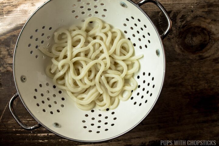 A colander with udon noodles that have been defrosted by running hot tap water over it.