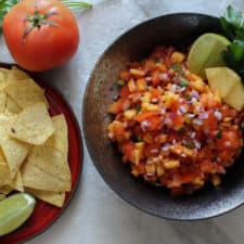 Pineapple Salsa in a large black bowl served with a side of tortilla chips