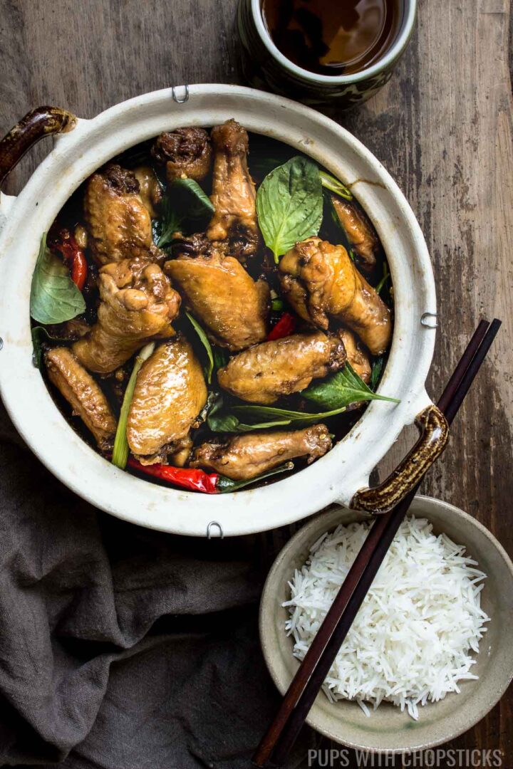 Three Cup Chicken in a clay pot with a bowl of white rice and a cup of tea