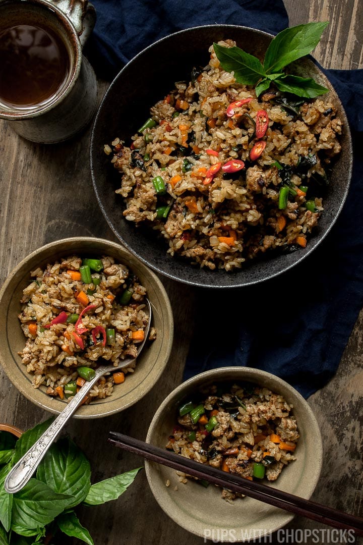 A large bowl of thai basil turkey fried rice with 2 small servings on the side with a cup of tea