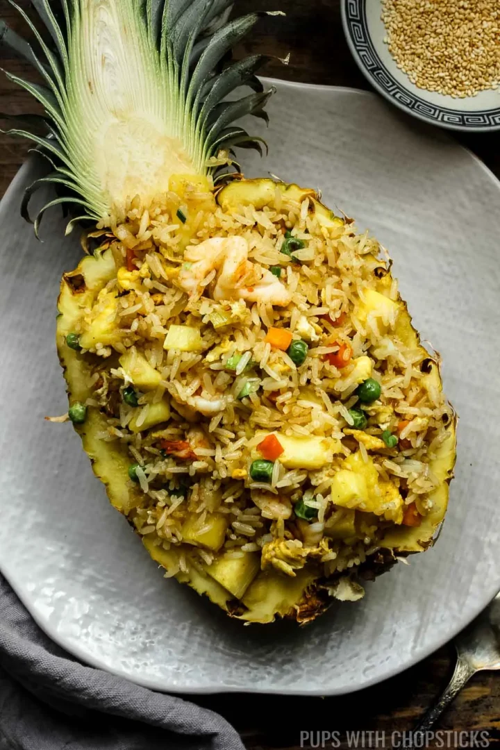 thai pineapple fried rice in a pineapple bowl on a white plate.