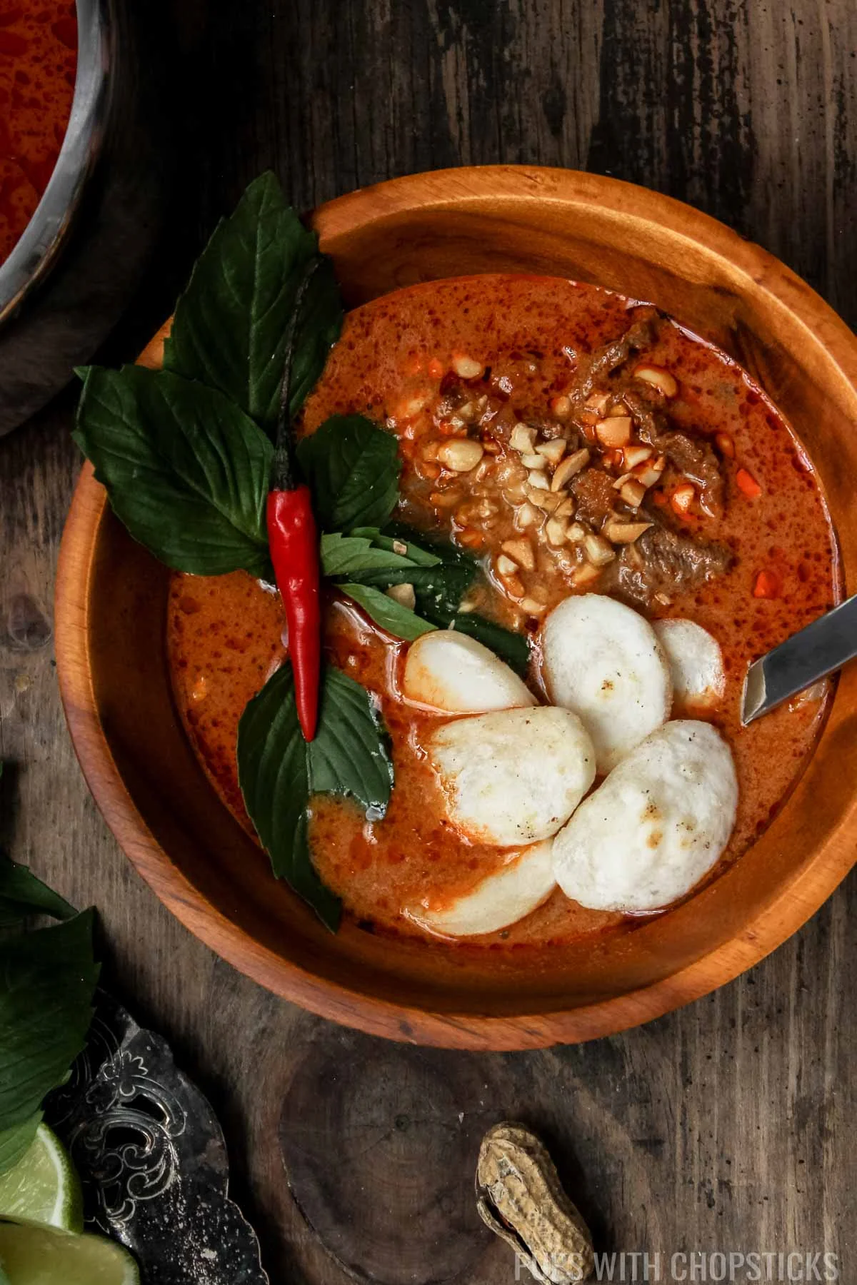 Closeup of Coconut Thai Red Curry served in a wooden bowl with rice cakes.
