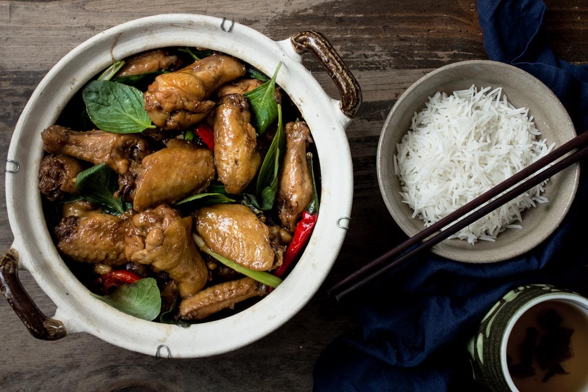 Three Cup Chicken in a clay pot with a bowl of white rice and a cup of tea