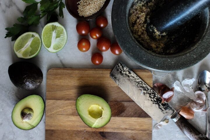 Cutting avocados in half on cutting board.