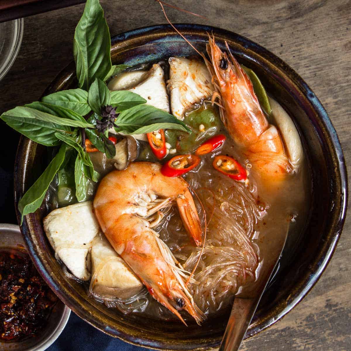  A bowl of tom yum soup with whole shrimp and garnished with Thai basil