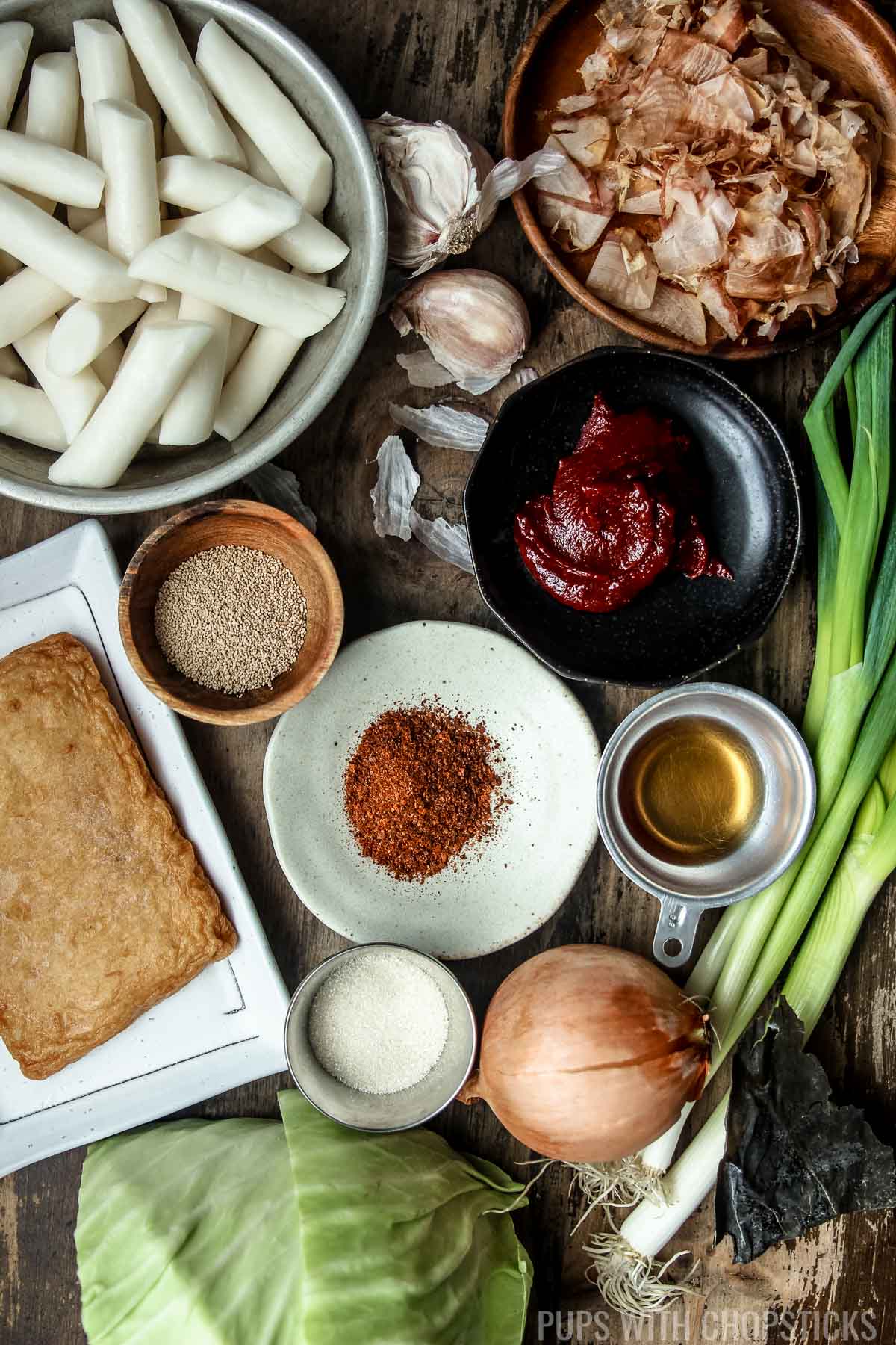 Ingredients for tteokbokki (rice cakes, bonito flakes, gochujang, gochugaru, garlic, dashi powder, fish cakes, sesame oil, onion, sugar)