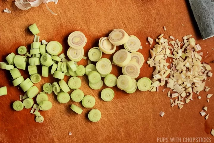 A orange cutting board showing lemongrass being finely chopped
