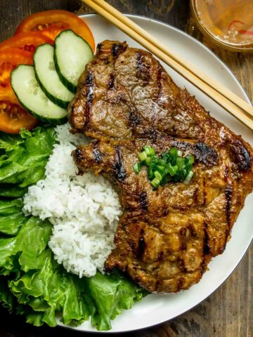 vietnamese lemongrass porkchops served with rice on a white plate.