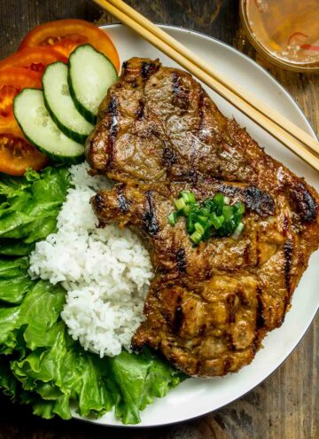 vietnamese lemongrass porkchops served with rice on a white plate.