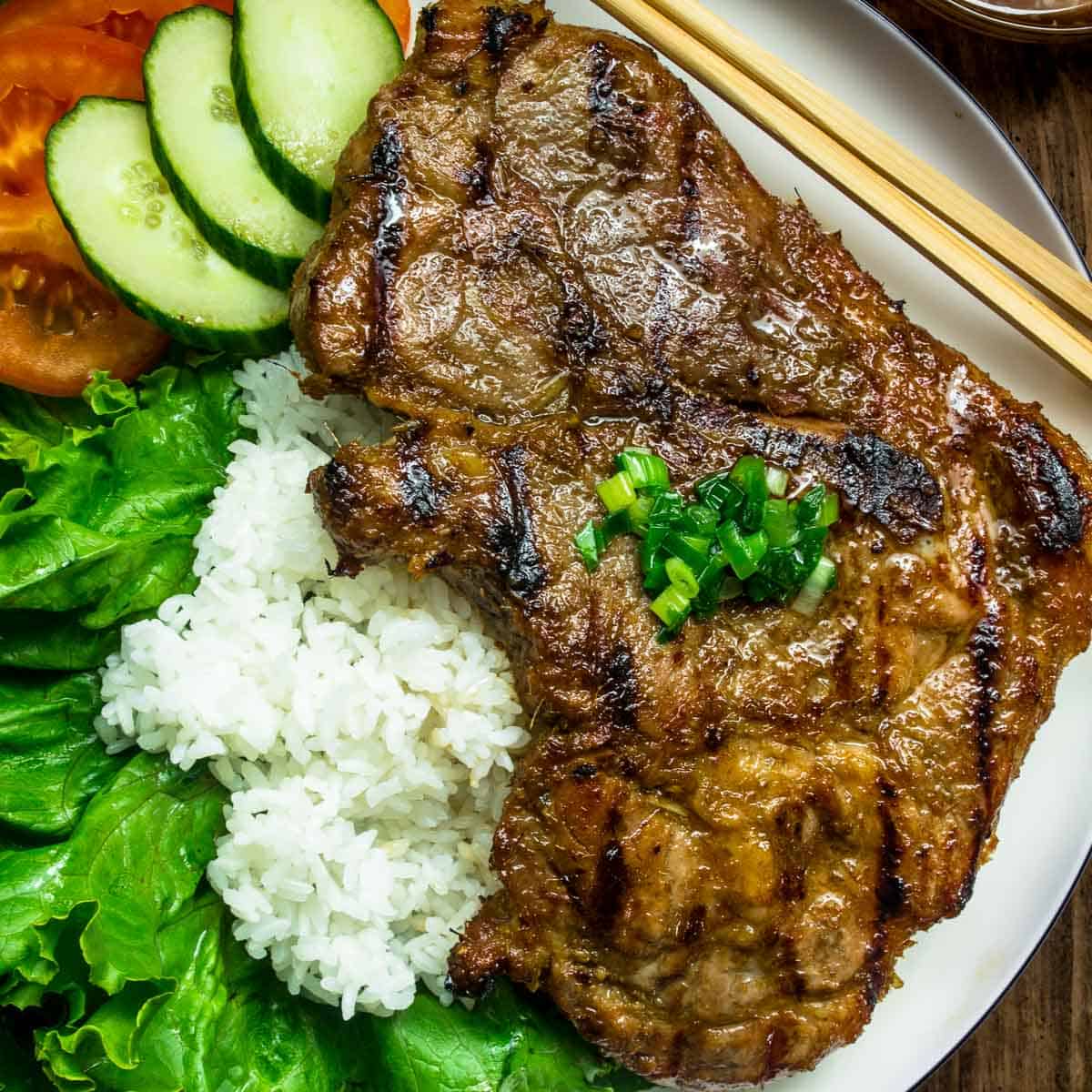 Closeup of Vietnamese lemongrass porkchop on white plate served with white rice