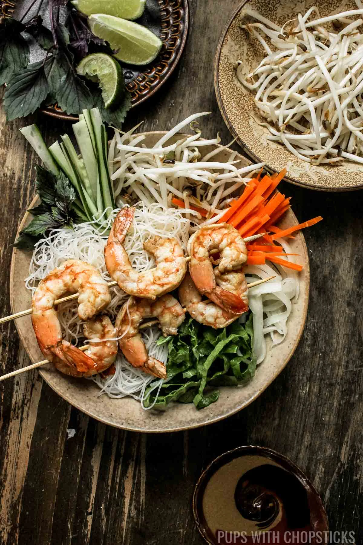 Vietnamese vermicelli noodle bowl served with bean sprouts and limes on the side with shrimp on top.