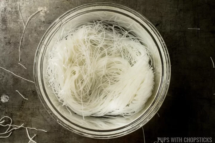 Vermicelli noodles soaked in boiling water in a glass bowl