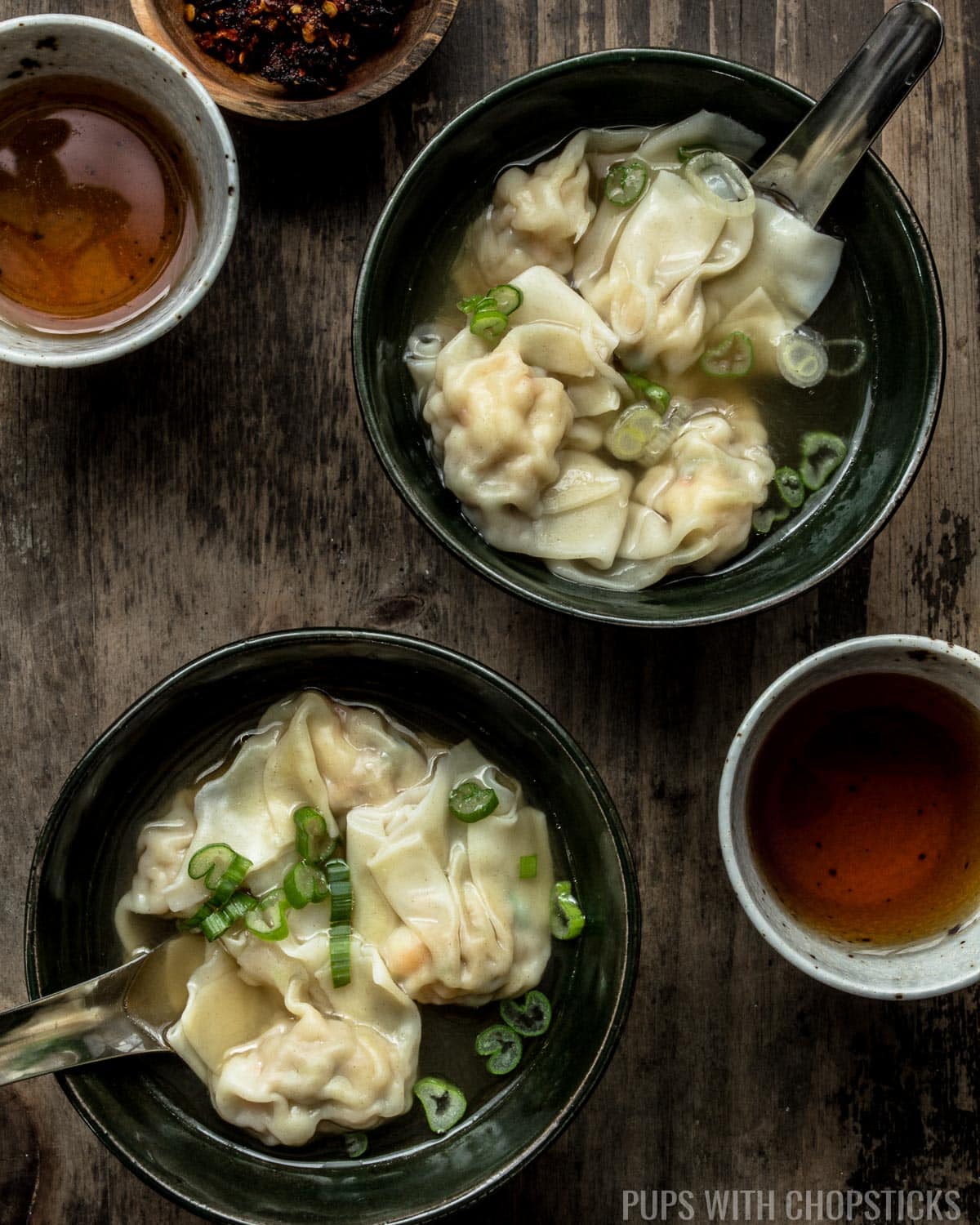 2 small bowls with wonton dumplings in broth served with tea
