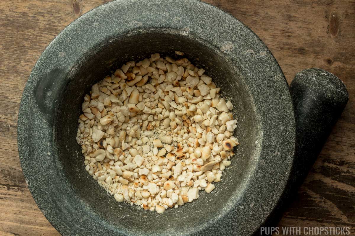 Mortar and pestle with roasted peanuts crushed inside