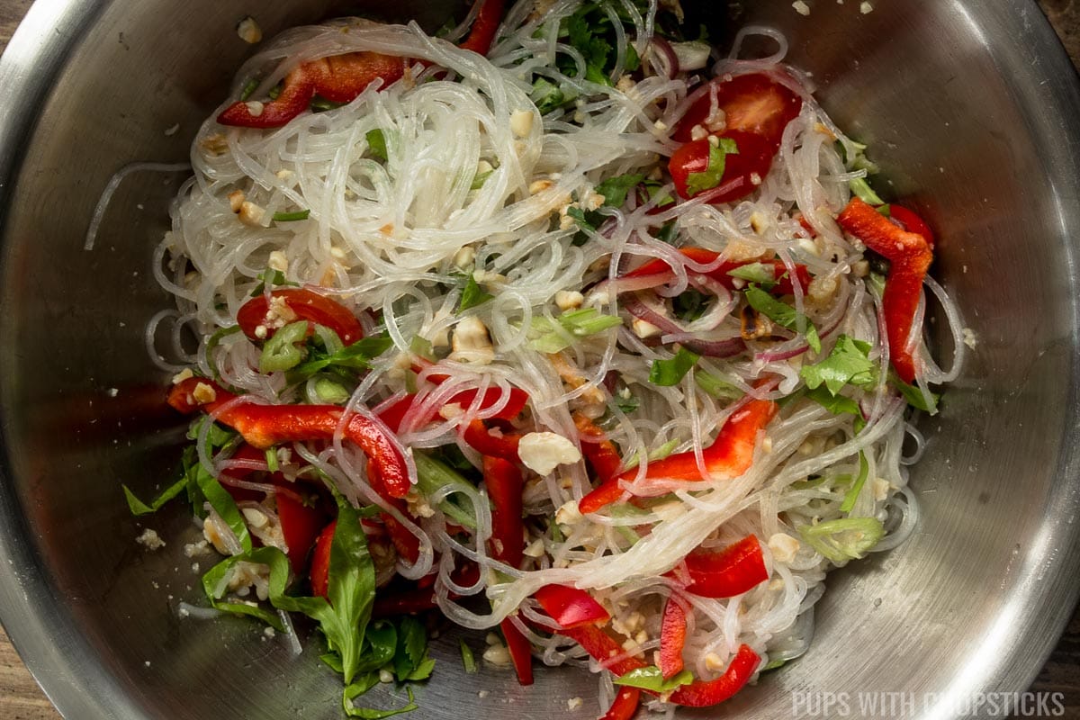 A large metal bowl with Thai glass noodle salad all mixed together.