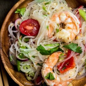 Close up of yum woon sen noodle salad with shrimp and glass noodles on a wooden plate